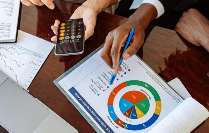 Two business professionals discussing financial documents and strategies at an office desk.
